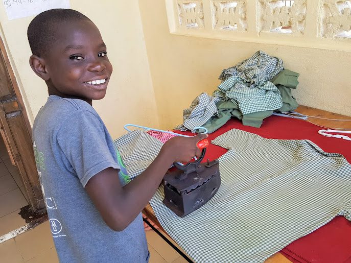 A Smiling Little Boy Ironing Shirts