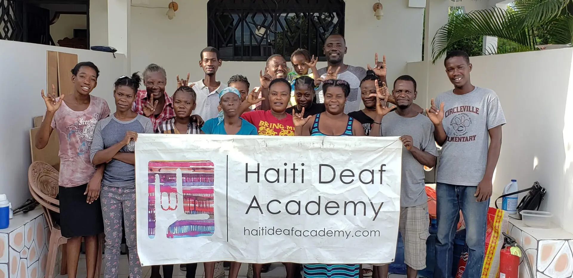 A Group of People Holding Haiti Deaf Academy Banner